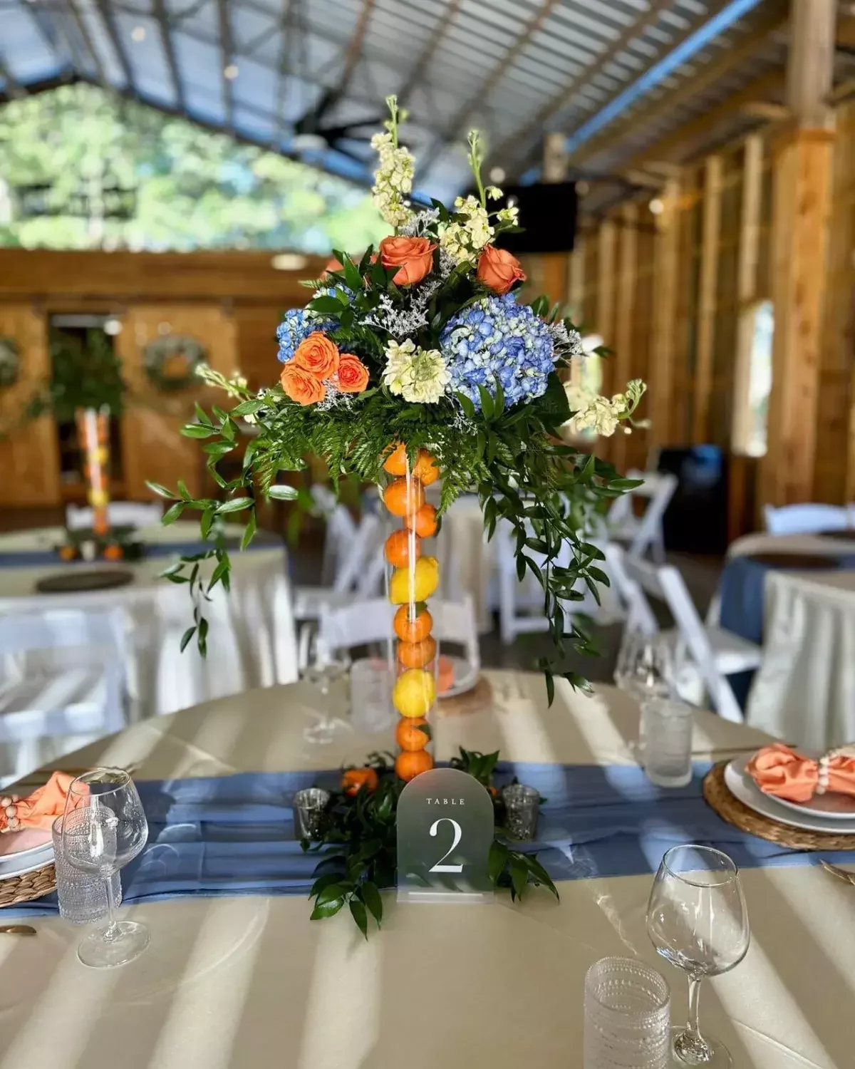 Tall Florida citrus centerpiece of oranges and lemons topped with blue hydrangea at a wedding reception