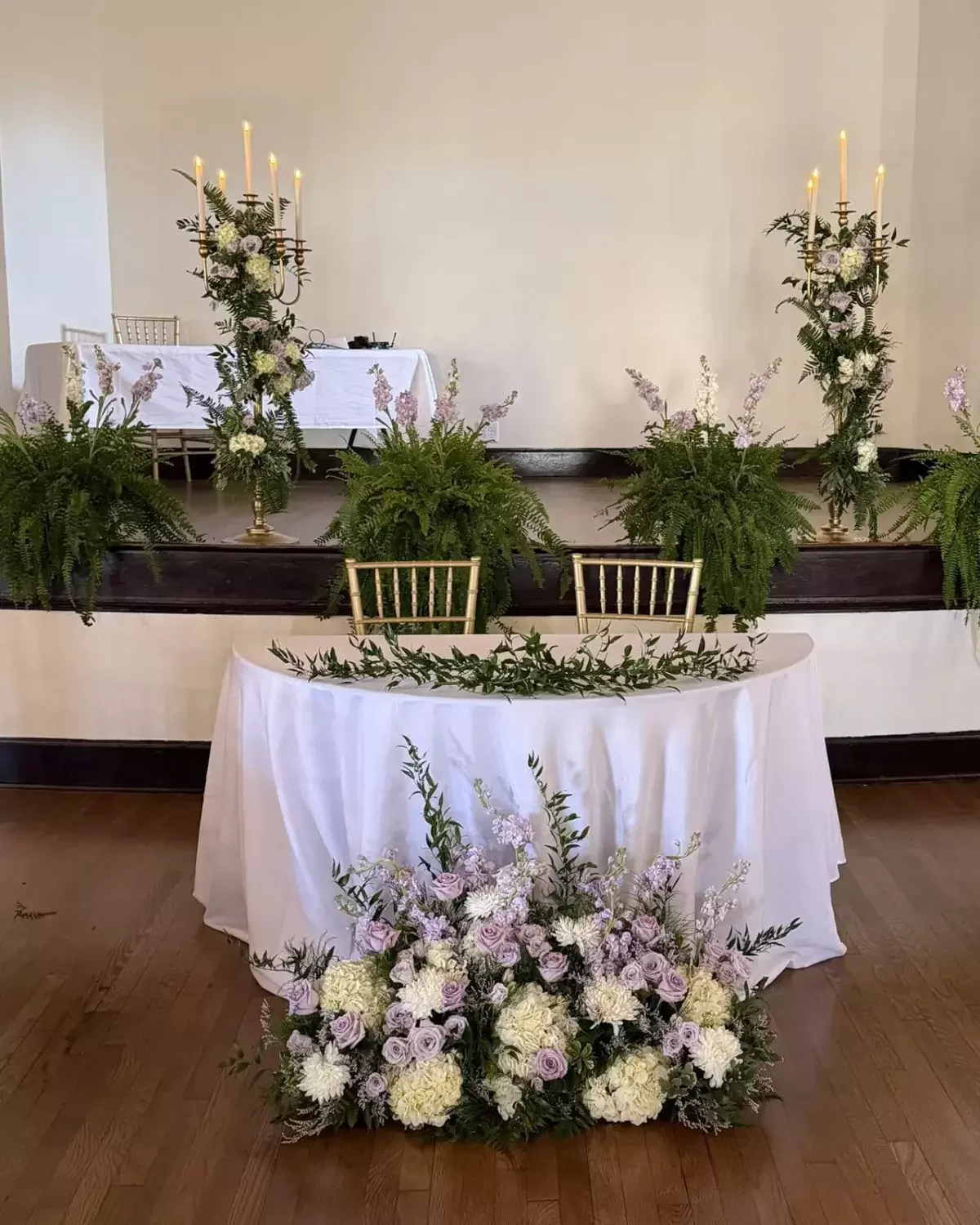Sweetheart table with lavender and white ground florals and candelabras at a luxury wedding reception